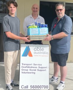 One Light Charity volunteers hands over gifts to two older men doing volunteer work