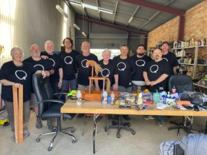 Group phot of men with black t-shirts in a work shed
