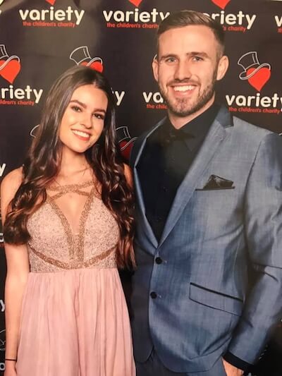 Image of a young man in a suit and a young lady in an evening dress in front of Variety banner