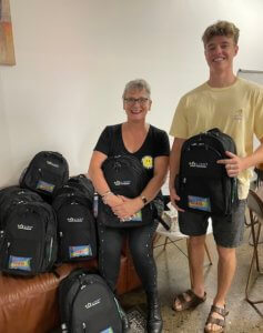 Young man and woman standing in front of One Light Charity backpacks