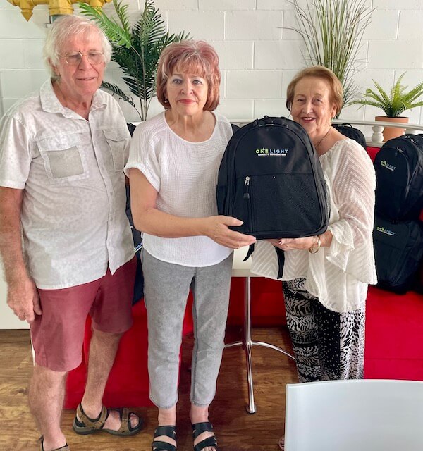 Three elderly people receiving One Light Charity Backpacks for the homeless