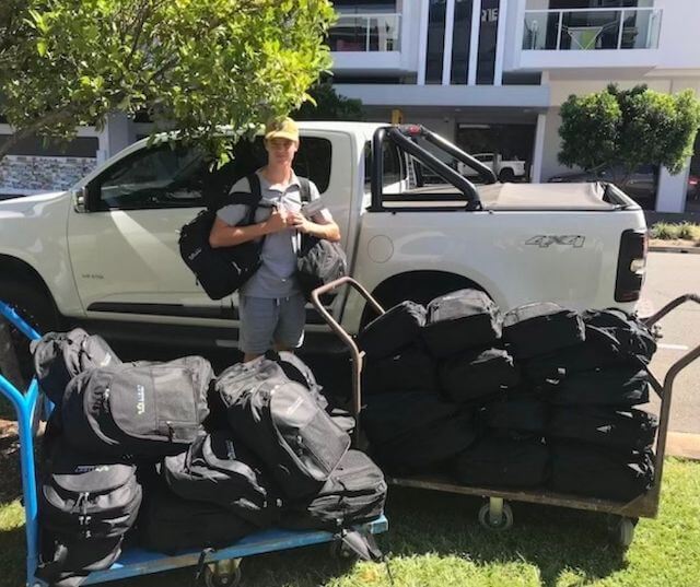 Teenager volunteer standing in front of white ute with trollies loaded with backpacks