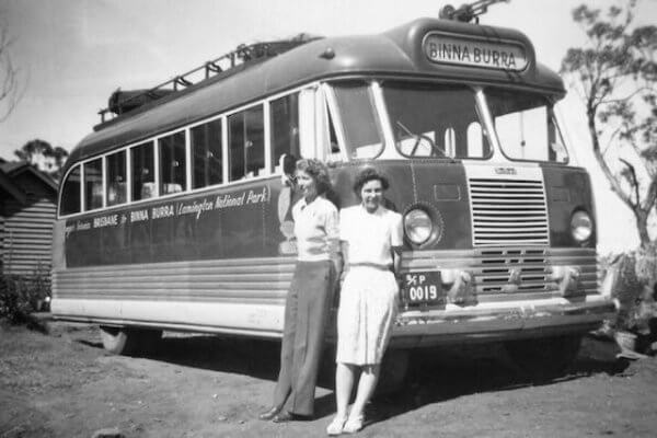 Old historical black and white photo od Binna Burra bus with two young women standing next to the bus.
