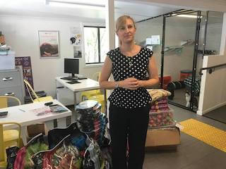 Photo of lady with black pants standing in an office at the AWL Beenleigh in front of products donated By One Light Charity Foundation and Bartercard Members