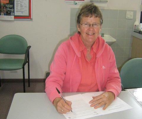 Older lady signing papers and smiling