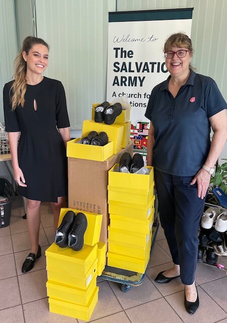Two ladies standing infront of school shoes in yellow boxes