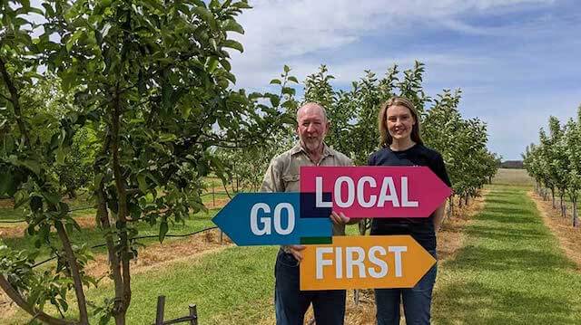 Farmer and daughter holding signs that says Go Local First