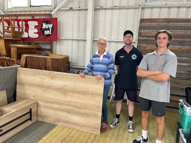 Two men standing with older women delivering furniture