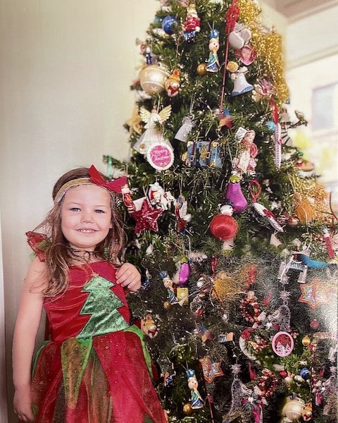 Little girl standing infant of Christmas tree