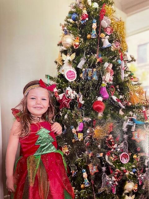Little girl standing infant of Christmas tree